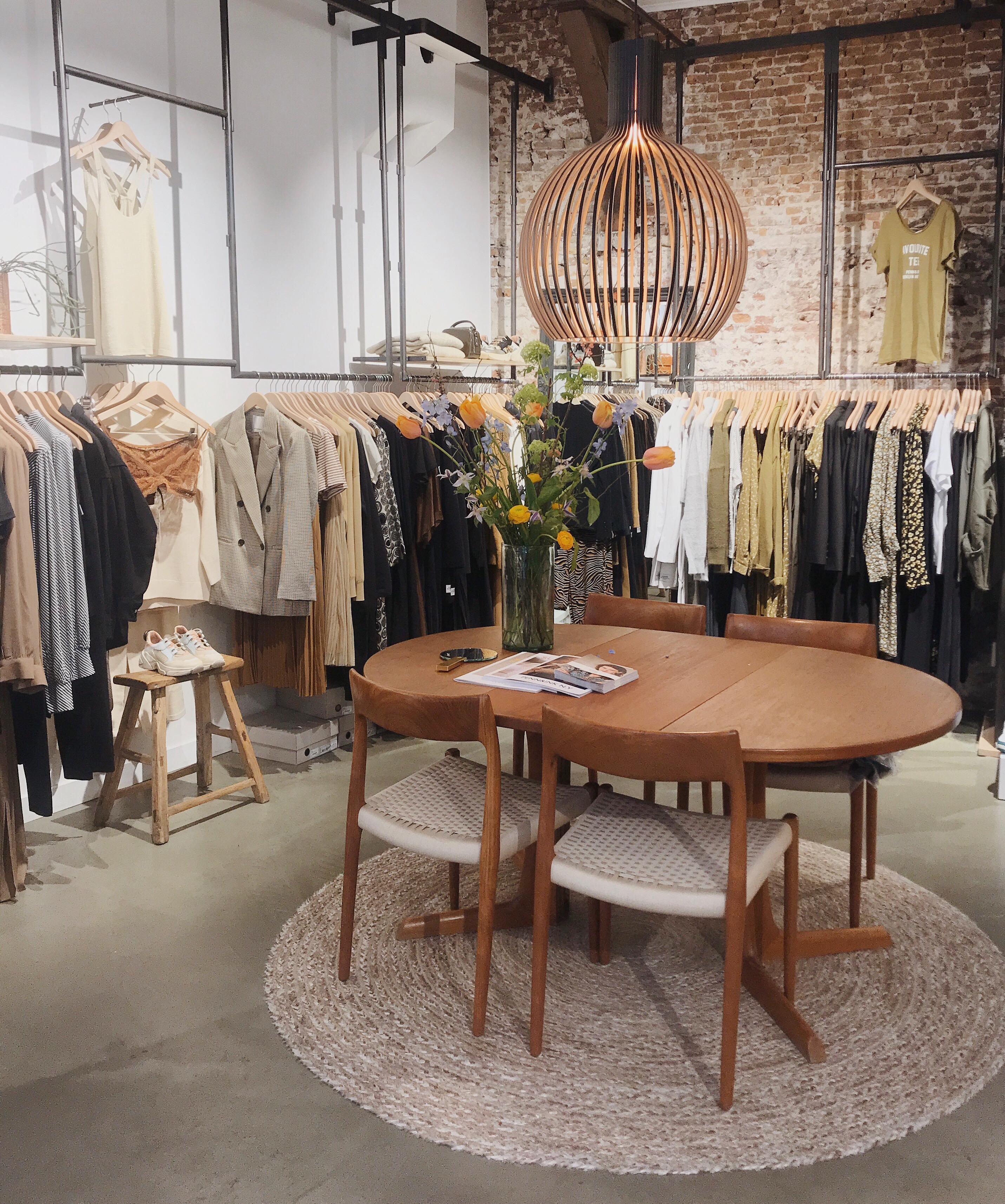 Kledingrekken en tafel met bloemen in de winkel Butik Alkmaar